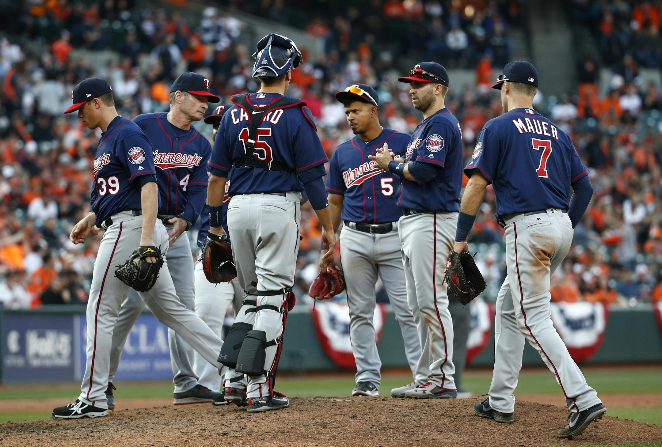 Minnesota Twins relief pitcher Trevor Hildenberger, left, walks off the field after being relieved by manager Paul Molitor, second from left, in the 10th inning on opening day in Baltimore.
