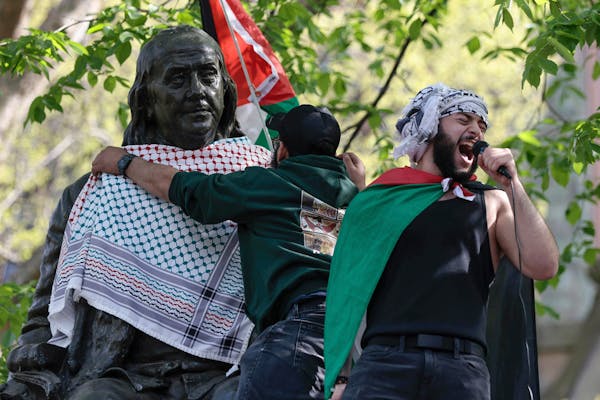 Qais Dana protests as a person puts a scarf on a Ben Franklin statue on Penn's campus during a pro-Palestinian demonstration in Philadelphia on Thursd