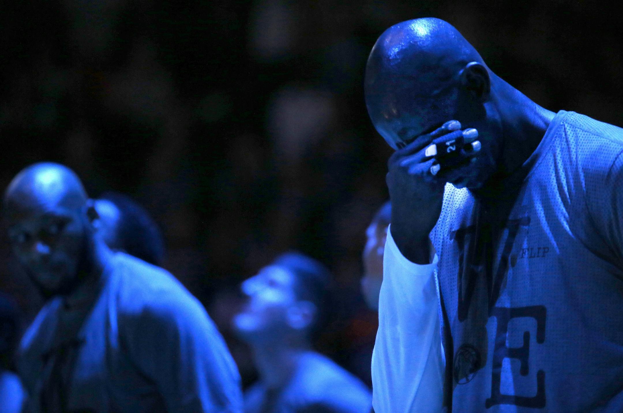 Minnesota Timberwolves forward Kevin Garnett put his hand to his face as he watched a tribute to the late Flip Saunders before the start of Monday night's home opener.