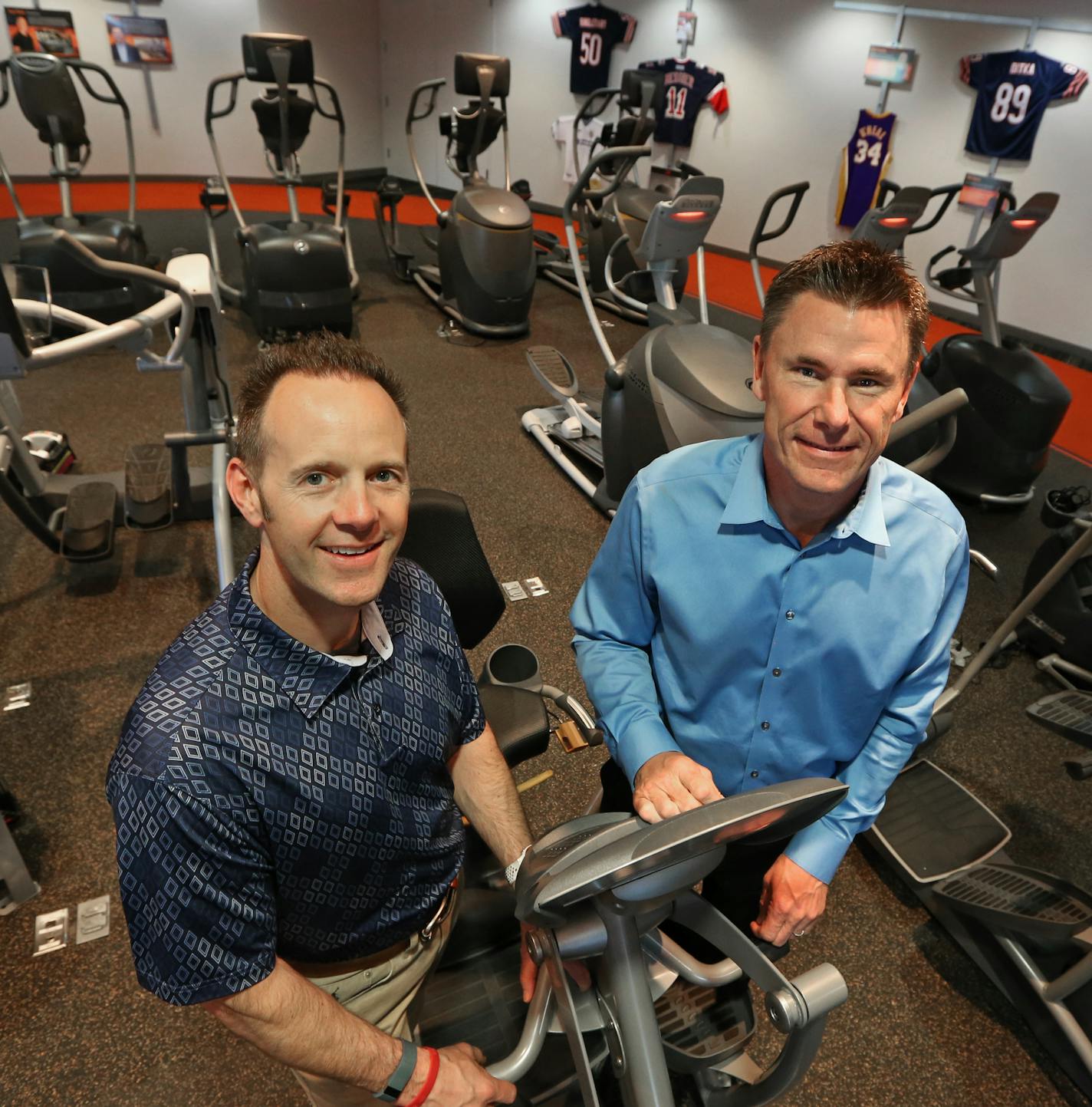 Octane Fitness founders Tim Porth, left, and Dennis Lee are surrounded by their product at the company headquarters showroom in Brooklyn Park. Employees can get their own machine after three months of employment.