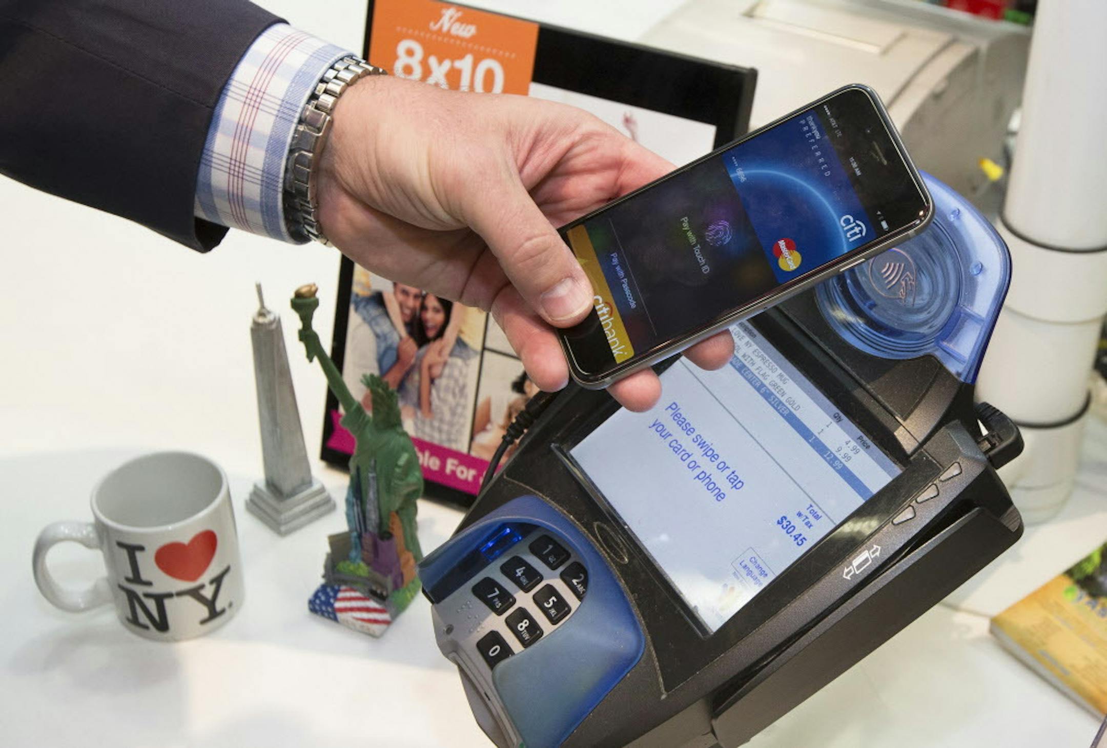 IMAGE DISTRIBUTED FOR MASTERCARD - A customer makes a purchase with a MasterCard using Apple Pay on the iPhone 6 at Walgreens in Times Square, Monday, Oct. 20, 2014, in New York. The service launched Monday. (John Minchillo/AP Images for MasterCard)
