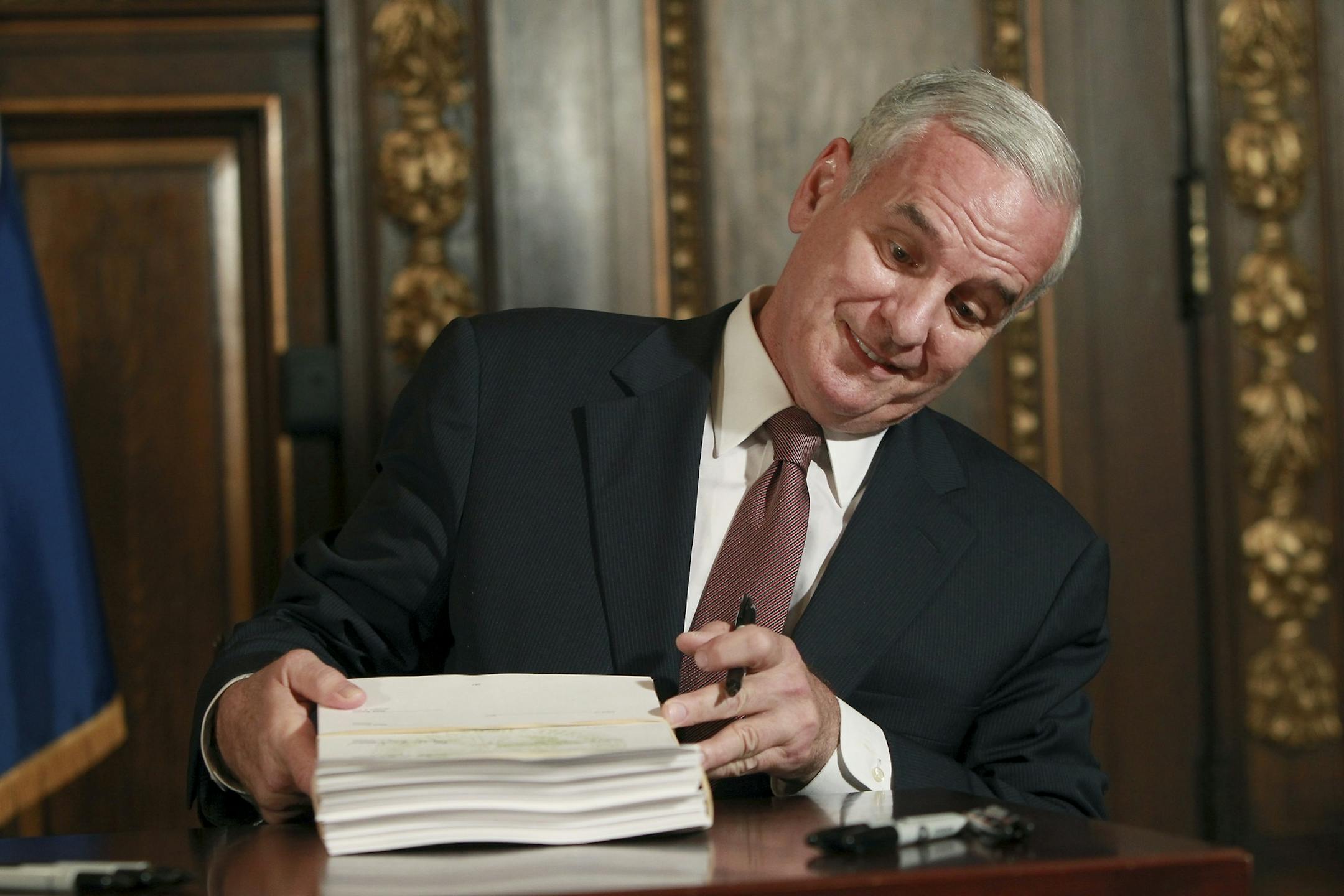 Gov. Mark Dayton signs bills ending the government shutdown.