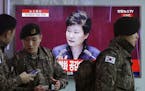 South Korean army soldiers pass by a TV screen showing the live broadcast of South Korean President Park Geun-hye's speech, at the Seoul Railway Stati