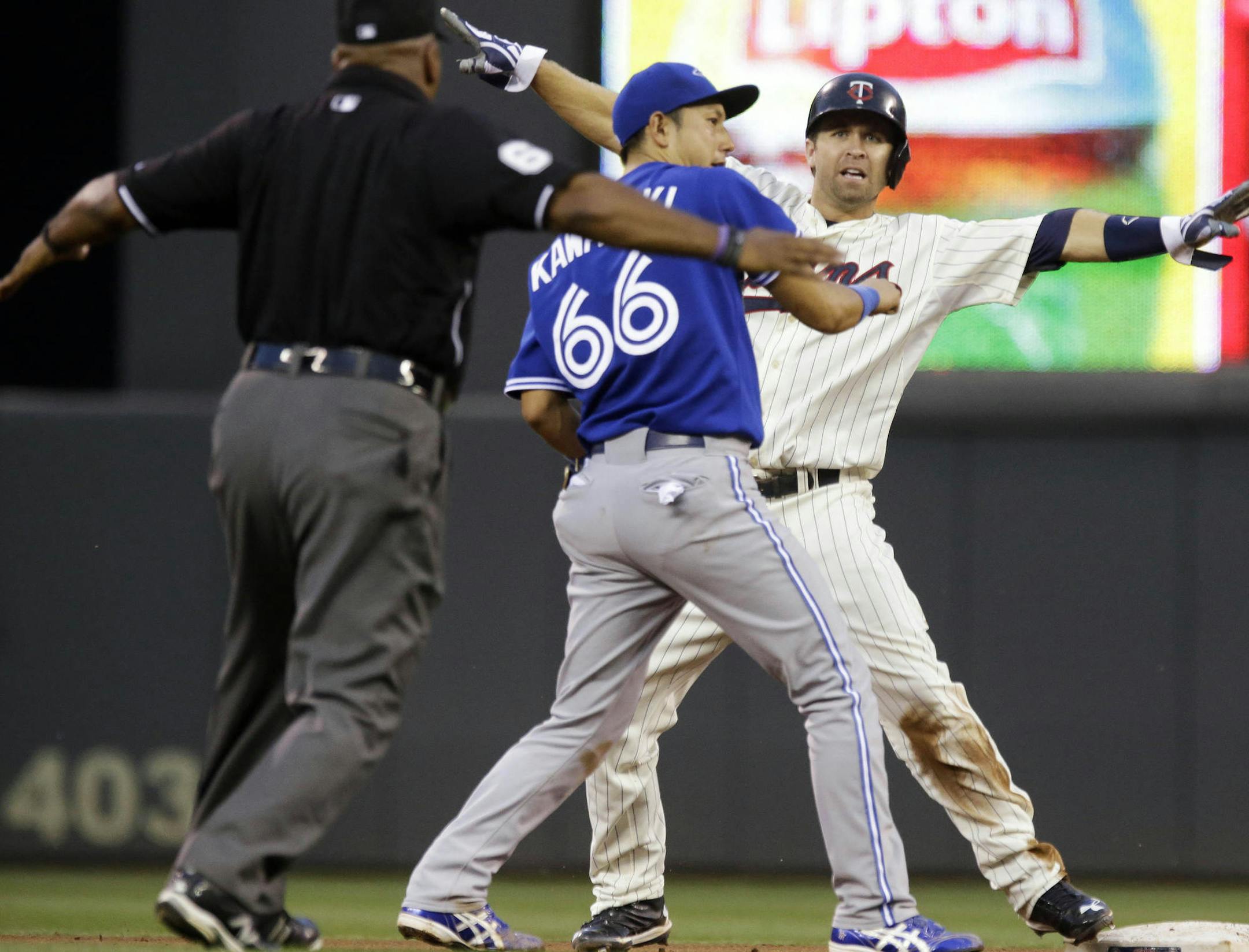 Minnesota Twins' Brian Dozier, right, signals that he is safe after Toronto Blue Jays second baseman Munenori had to go high for an errant throw from third baseman Brett Lawrie during the fourth inning of a baseball game, Saturday, Sept. 7, 2013, in Minneapolis. (AP Photo/Jim Mone)