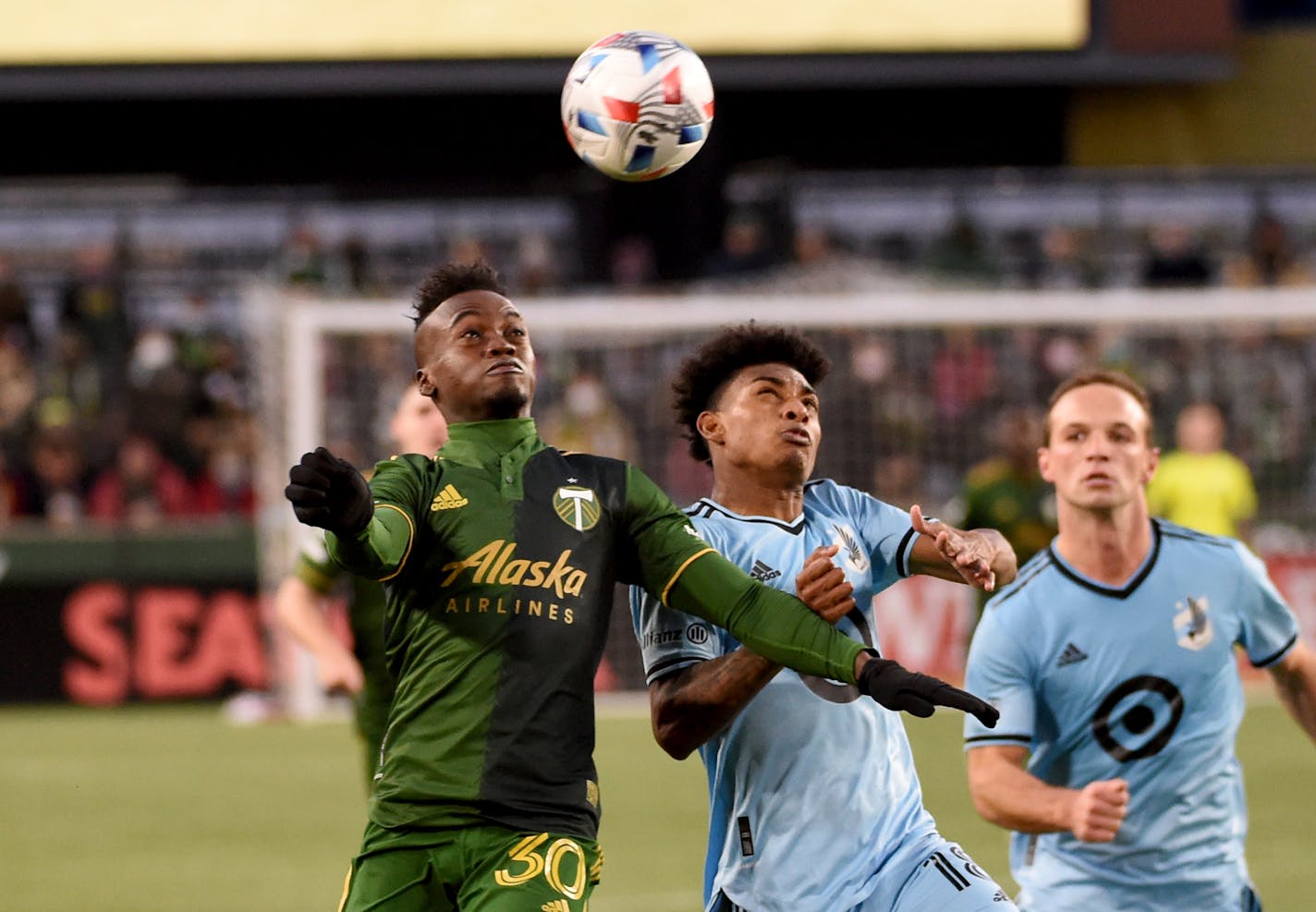 Portland Timbers midfielder Santiago Moreno, left, and Minnesota United midfielder Joseph Rosales, center, go after a ball during the second half of an MLS soccer match in Portland, Ore., Sunday, Nov. 21, 2021. (AP Photo/Steve Dykes)