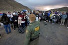 A Border Patrol agent asks asylum-seeking migrants to line up after the group crossed the border with Mexico on Feb. 2 near Jacumba Hot Springs, Calif