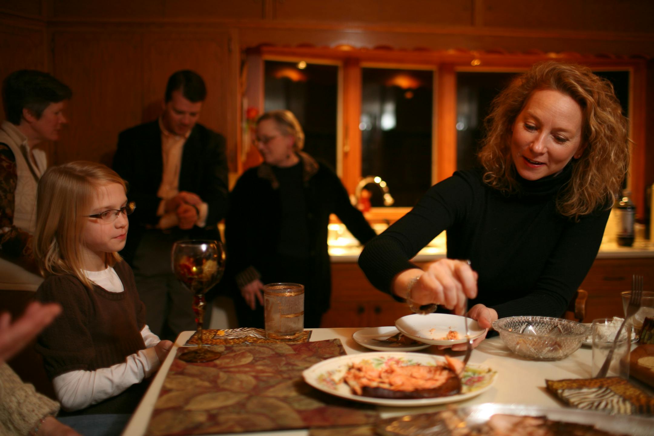 Jennifer Snyder served some of Bill Klein's salmon at the gathering at his Stillwater home Thursday night. At left is Snyder's daughter, Ella, 10. At rear were guests Laurie Carlson, left, Dave Snyder, and Linda Klein who hosted the gathering with her husband, Bill.