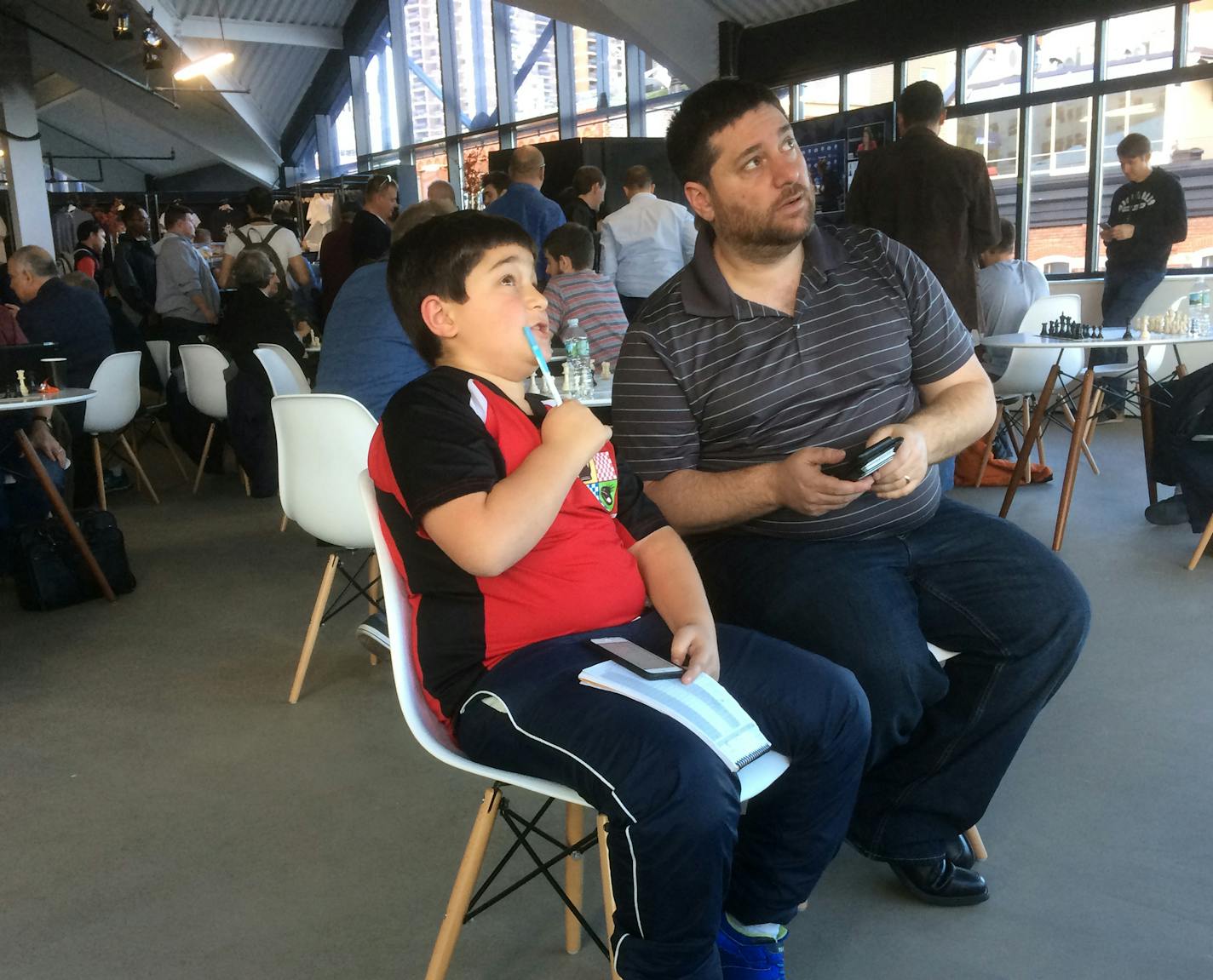 Ethan Litman and his dad Dana Litman, of Golden Valley, watched moves on a TV monitor at the World Chess Championship match in New York City Friday. credit: Dennis Mcgrath - Star Tribune 11/11/16