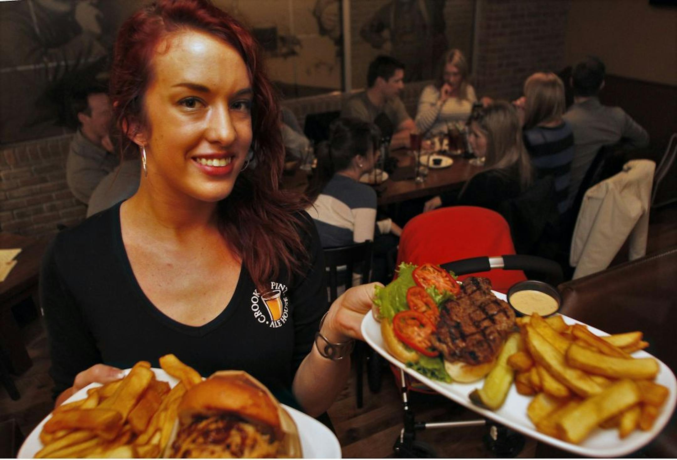 The Crooked Pint Ale House in Minneapolis recently completed a remodeling resulting in a two tier customer space and a central bar. The band, Hookers and Blow played to a crowd on a recent night. Waitress Ellen Rock delivered burgers and fries to customers.