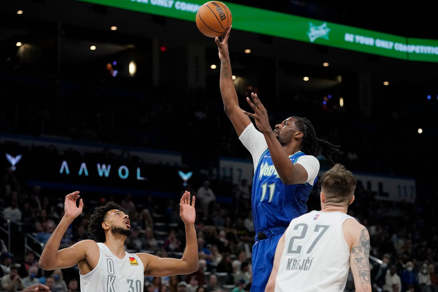 Timberwolves center Naz Reid shoots between Oklahoma City center Olivier Sarr (30) and guard Vit Krejci (27) in the first half Friday