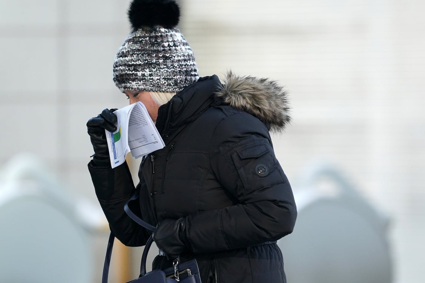 A woman used papers to try and block the wind from her face while walking in downtown Minneapolis.