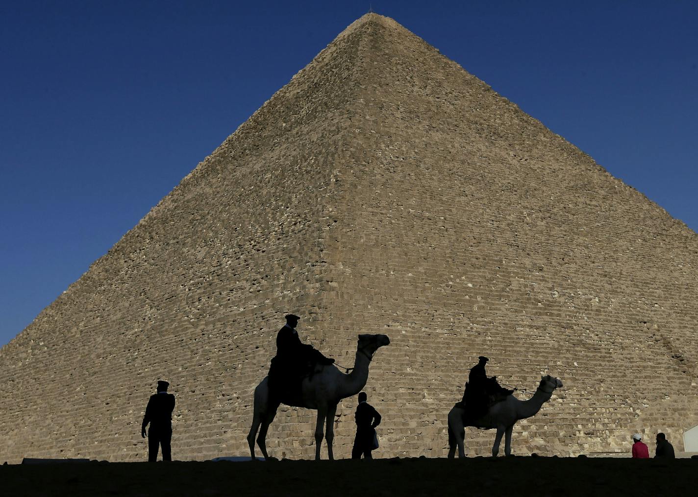 FILE - In this Dec. 12, 2012 file photo, policemen are silhouetted against the Great Pyramid in Giza, Egypt. Scientists have found a previously undiscovered hidden chamber in Egypt's Great Pyramid of Giza, the first such discovery in the structure since the 19th century. In a report published in the journal Nature on Thursday, Nov. 2, 2017, an international team says the 30-meter (yard) void deep within the pyramid is situated above the Grand Gallery, and has a similar cross-section. (AP Photo/H