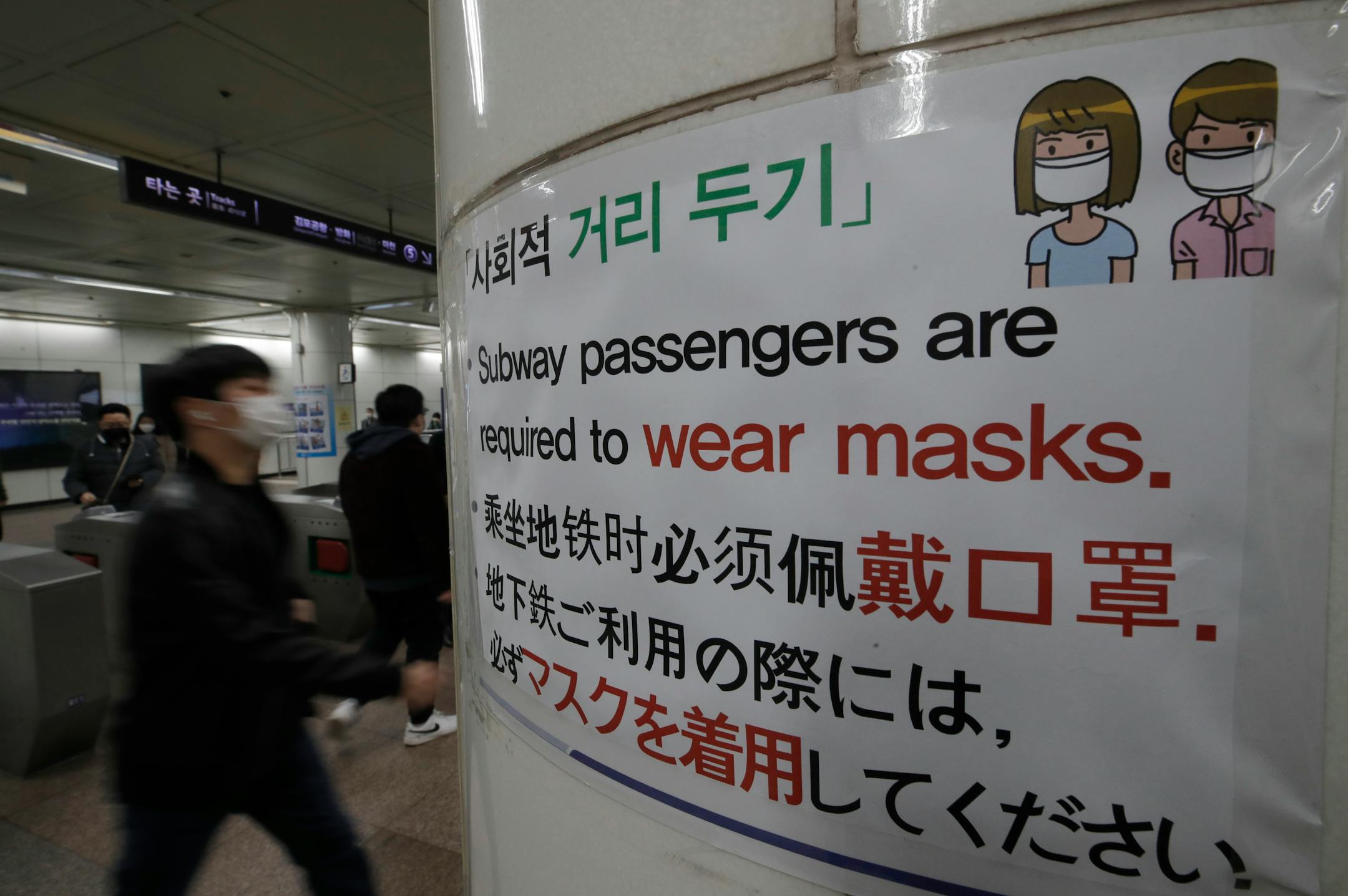 People wearing face masks as a precaution against the coronavirus, walked past a banner at a subway station in Seoul, South Korea on Friday. South Korea has reported its biggest daily jump in COVID-19 cases in 70 days as the government began fining people who fail to wear masks in public. From Friday, officials started to impose fines of up to 100,000 won ($90) for people who fail to properly wear masks in public transport and a wide range of venues, including hospitals, nursing homes, pharmacie