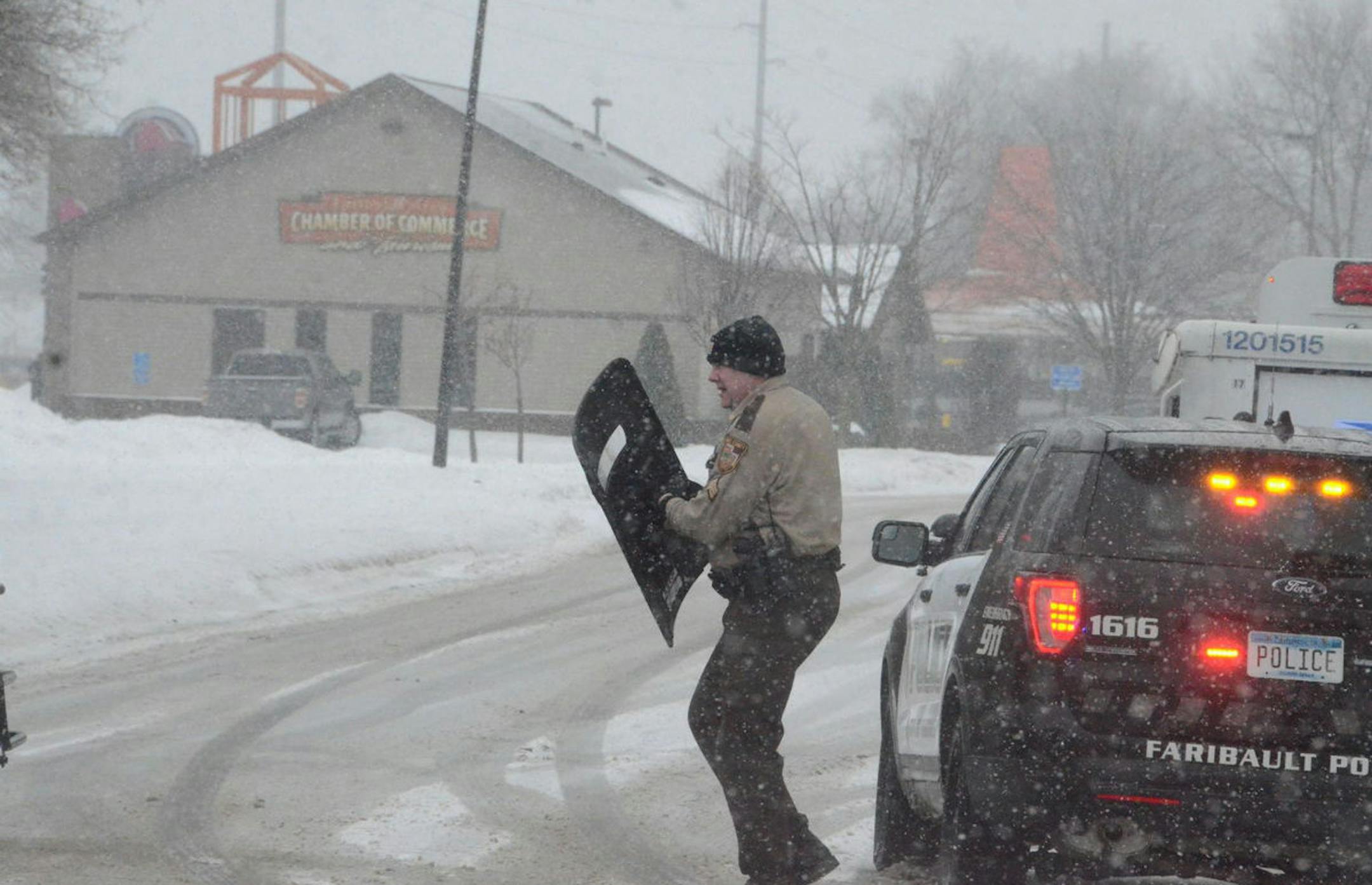 A RIce County deputy takes out equipment before heading toward the Faribault Chamber of Commerce building on Wilson Ave. The road was blocked off at Seventh Street and Hwy 60 Friday afternoon.