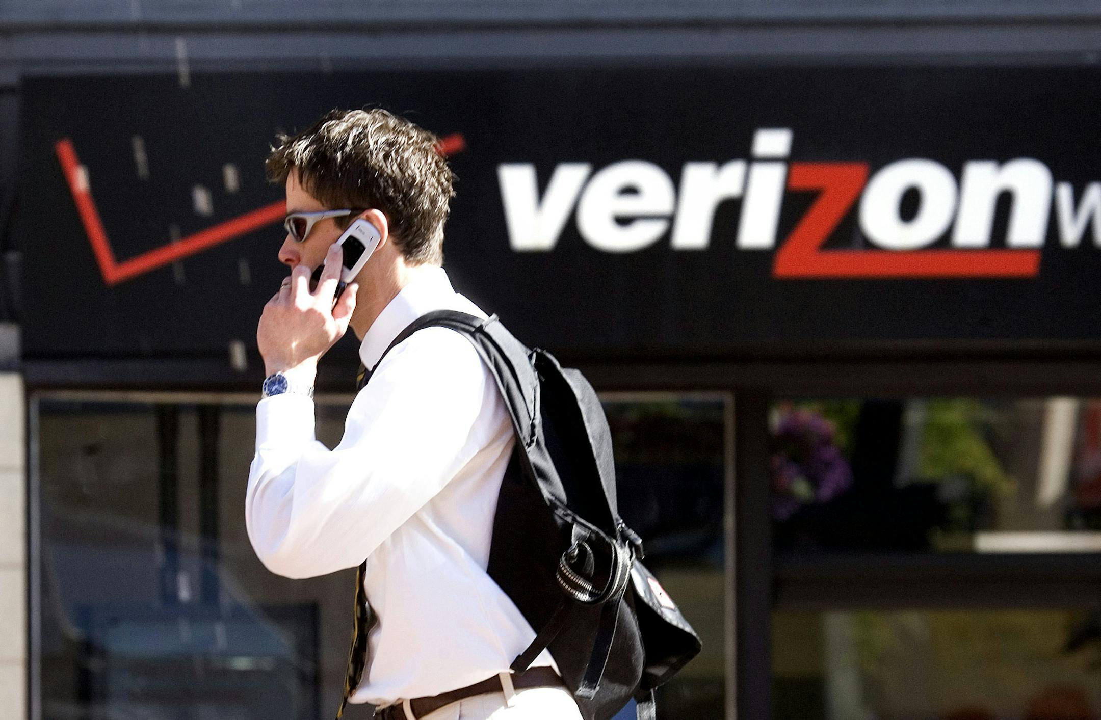 FILE - A Monday, July 28, 2008 photo from files showing Eric Roden speaking on his cell phone as he walks past a Verizon store in Portland, Ore., Britain's Vodafone PLC, one of the world's largest mobile phone companies, confirmed Thursday that it was in discussions with Verizon Communications to sell its operations in the United States. The British wireless provider is mulling its options for its 45 percent stake in the U.S.'s Verizon Wireless, of which Verizon Communications owns the other 55