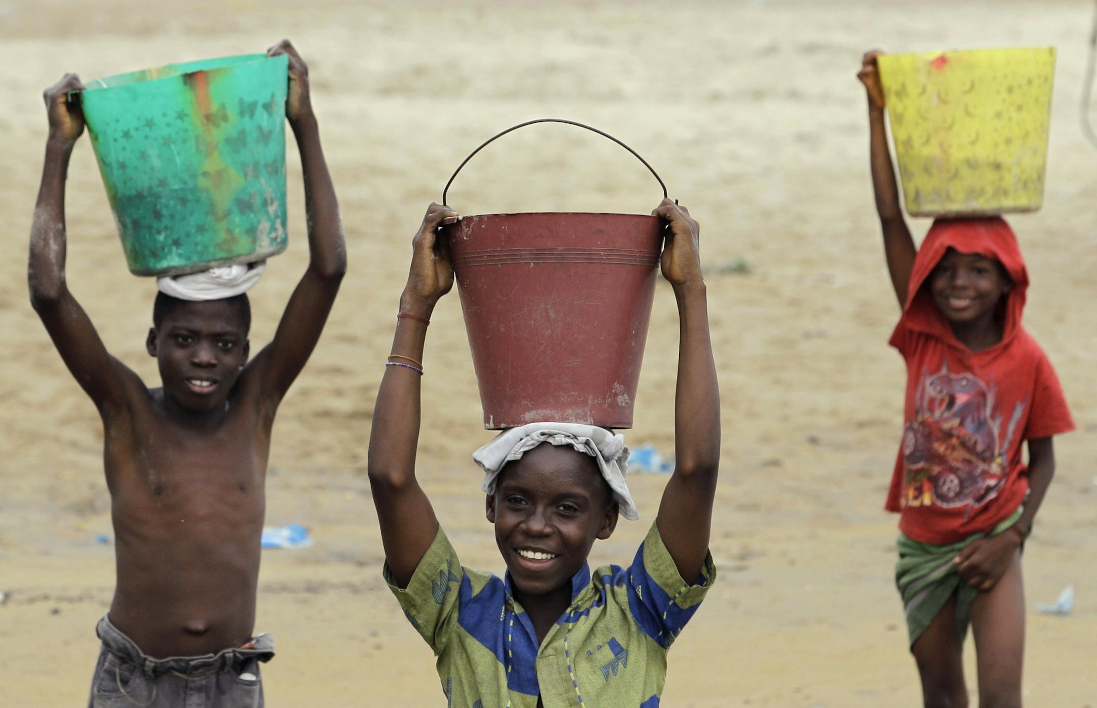 Boys carry buckets of beach sand to their homes, which their families will use to filter unclean well water, in the West Point neighborhood of Monrovia, Liberia, Friday, Nov. 11 2011.