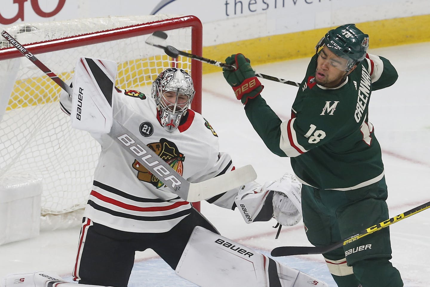 Minnesota Wild's Jordan Greenway, right, gets spun around as Chicago Blackhawks goalie Cam Ward deflects a shot during the first period of an NHL hockey game Thursday, Oct. 11, 2018, in St. Paul, Minn. (AP Photo/Jim Mone)