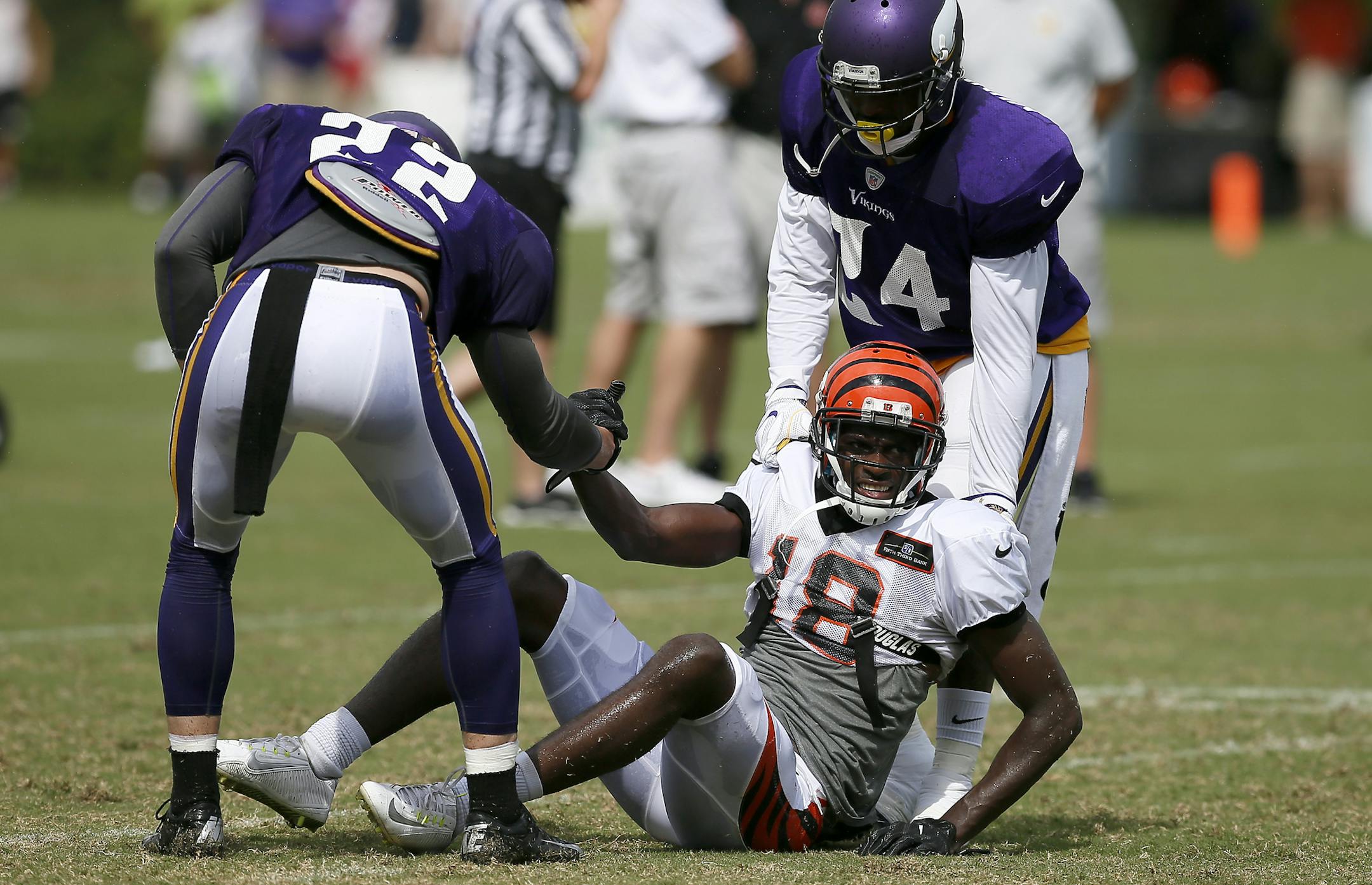 Cincinnati Bengals wide receiver A.J. Green (18) is helped up by Minnesota Vikings free safety Harrison Smith (22) and cornerback Captain Munnerlyn (24) after tumbling on a play during practice on Day 13 of training camp at the Paul Brown Stadium practice facility in downtown Cincinnati on Wednesday, Aug. 10, 2016. The Bengals and Vikings met on the practice field for the first of two joint practices ahead the first pre-season game of the year.