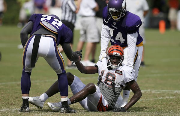 Cincinnati Bengals wide receiver A.J. Green (18) is helped up by Minnesota Vikings free safety Harrison Smith (22) and cornerback Captain Munnerlyn (2