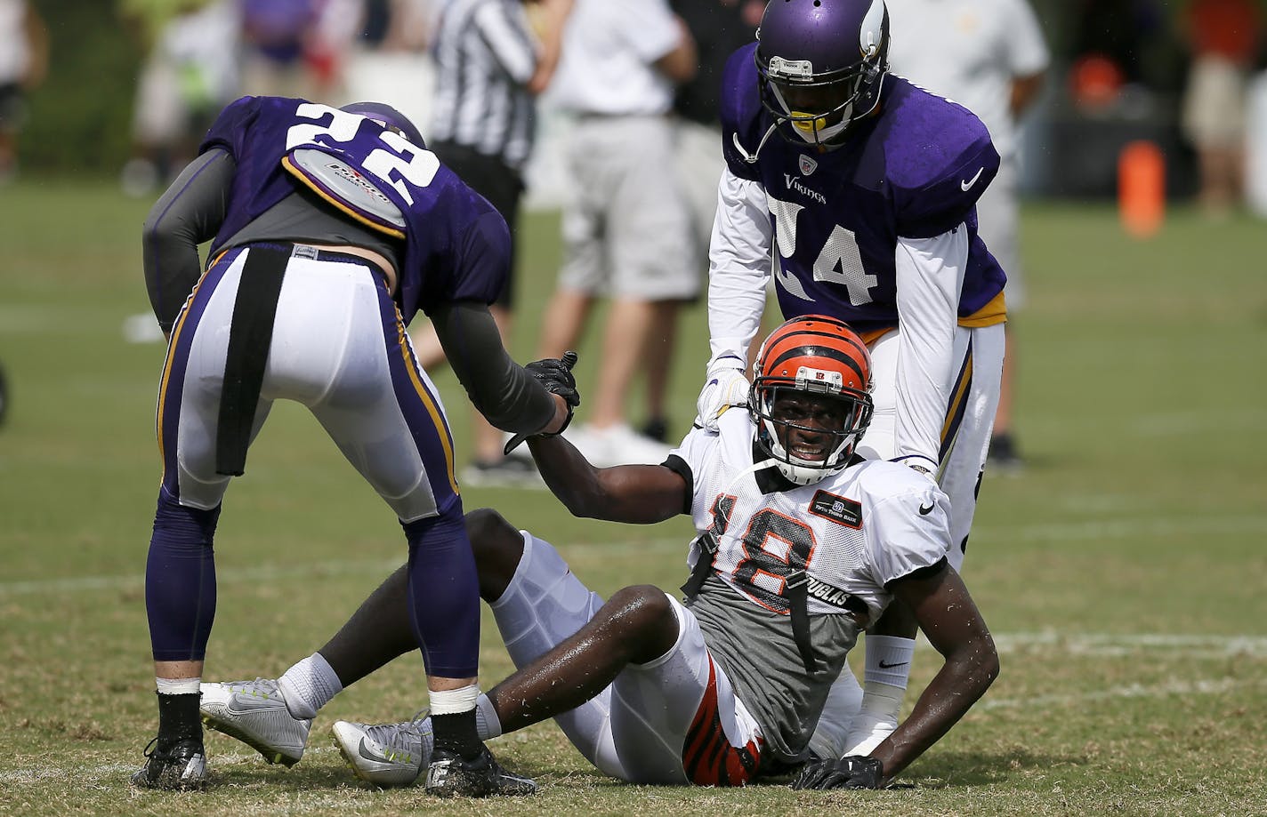 Cincinnati Bengals wide receiver A.J. Green (18) is helped up by Minnesota Vikings free safety Harrison Smith (22) and cornerback Captain Munnerlyn (24) after tumbling on a play during practice on Day 13 of training camp at the Paul Brown Stadium practice facility in downtown Cincinnati on Wednesday, Aug. 10, 2016. The Bengals and Vikings met on the practice field for the first of two joint practices ahead the first pre-season game of the year.