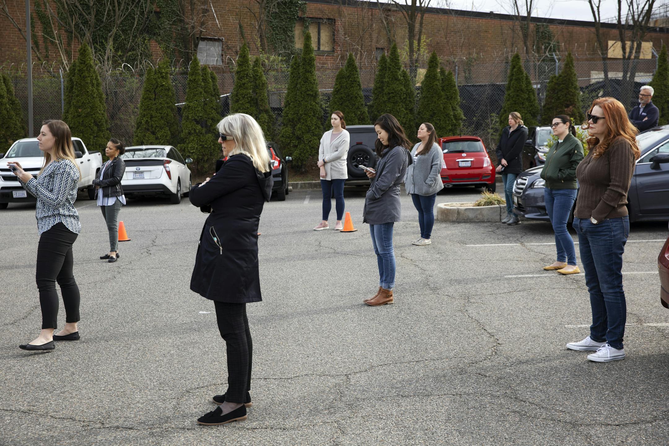 Staff of "Food and Friends," a food distribution service for people with life-challenging illnesses, practice social distancing by standing a clear distance apart as they listen to District of Columbia Mayor Muriel Bowser speak about the city's response to the coronavirus, Monday, March 16, 2020, during a news conference in Washington. (AP Photo/Jacquelyn Martin)