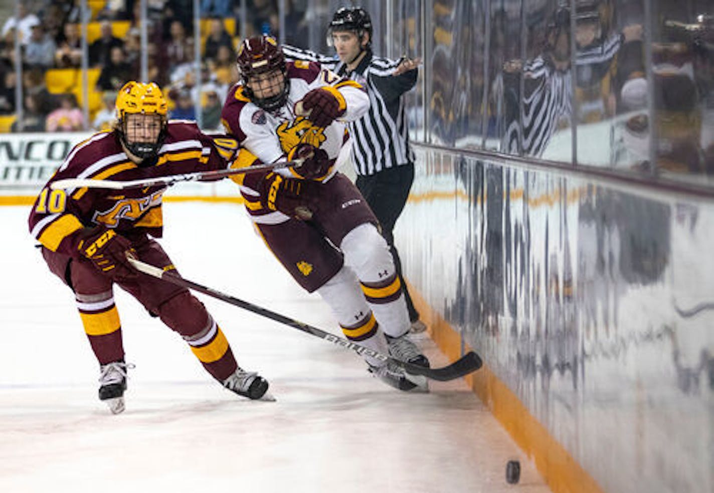 UMD forward Noah Cates (21) and UM defenseman Jackson Lacombe (10) race after a loose puck in the first period. ]