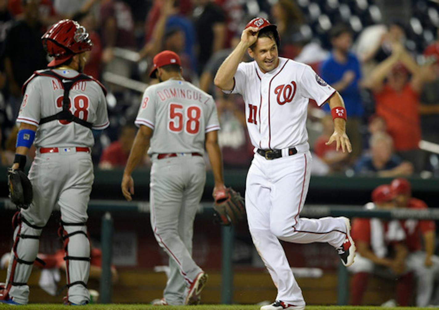 Washington Nationals' Ryan Zimmerman (11) runs toward home on his walk-off two-run home run during the ninth inning of a baseball game as Philadelphia Phillies relief pitcher Seranthony Dominguez (58) and catcher Jorge Alfaro (38) walk toward the dugout Wednesday, Aug. 22, 2018, in Washington. The Nationals won 8-7. (AP Photo/Nick Wass)