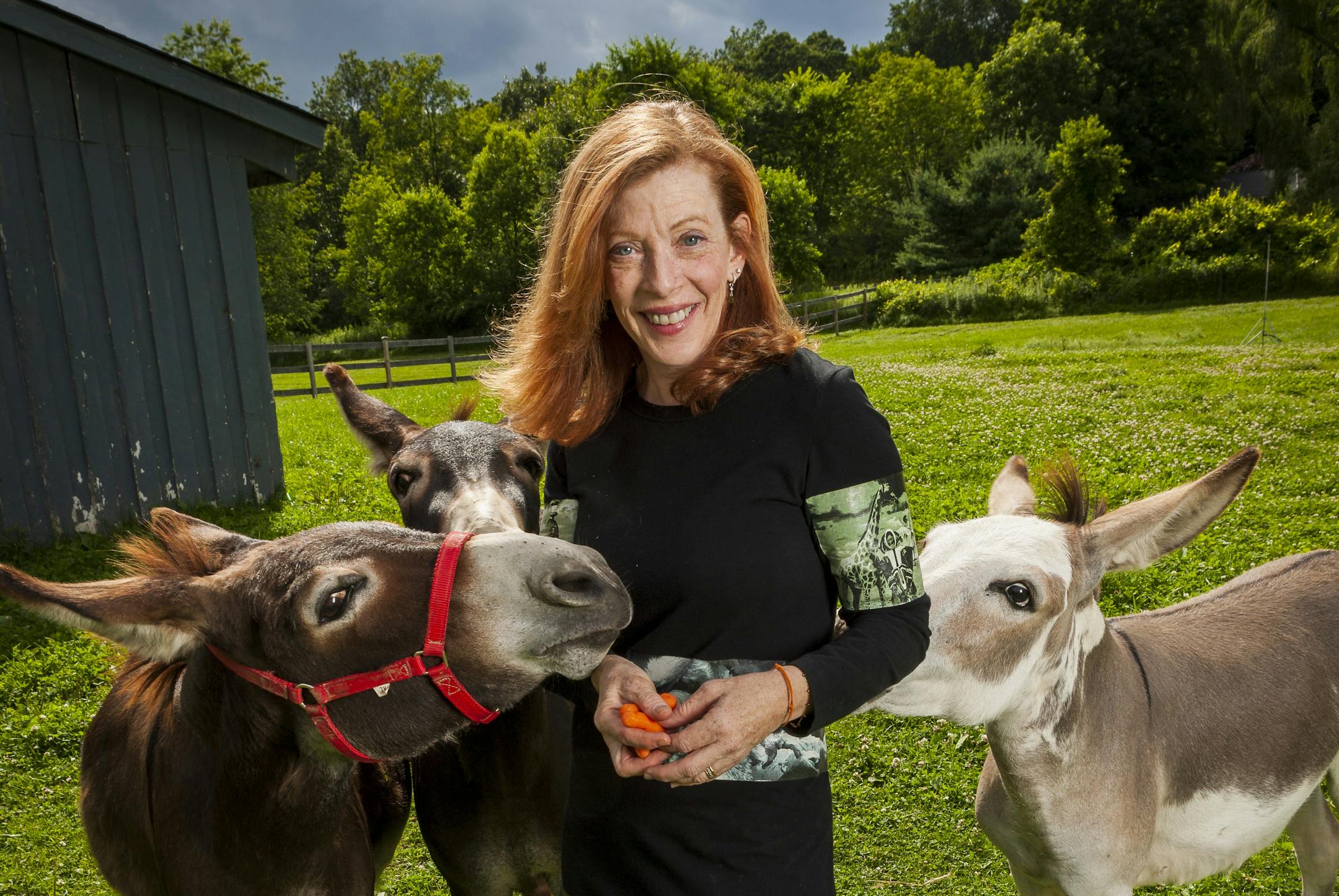 photo of author Susan Orlean in a field, feeding carrots to two horses