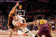 Illinois' Coleman Hawkins drives to the basket between the defense of the Gophers' Cam Christie (24) and Dawson Garcia during the first half of the Il