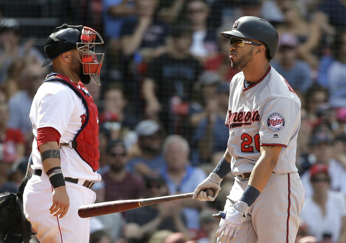 Minnesota Twins' Eddie Rosario, right, grimaces after striking out swinging as Boston Red Sox's Sandy Leon, left, looks on in the ninth inning of a baseball game, Sunday, July 29, 2018, in Boston. The Red Sox shut out the Twins 3-0. (AP Photo/Steven Senne)