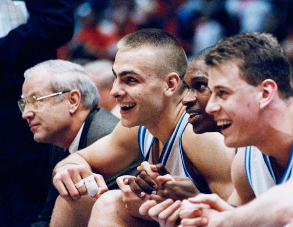 Eric Montross, Donald Williams and Pat Sullivan smile as they hold hands and sit out the last seconds of their overtime victory against Cincinnati at 