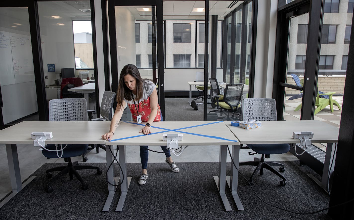 Jamie Rissi operations manager at Wellworth in St. Paul taped off a desk to help space out working areas in preparation for reopening. ] CARLOS GONZALEZ ¥ cgonzalez@startribune.com St. Paul, MN Ð May 14, 2020, Wellworth co-working operations managers are planning on moving desks and chairs around to tentatively open next week; It's on the top floor of the 428 building, COVID-19, Coronavirus