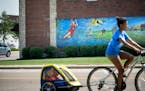 Anna Dalbec peddled past the Lindsay Whalen mural with twins Haeden and Chase in tow. She babysits for them and they were on their way to McDonalds do