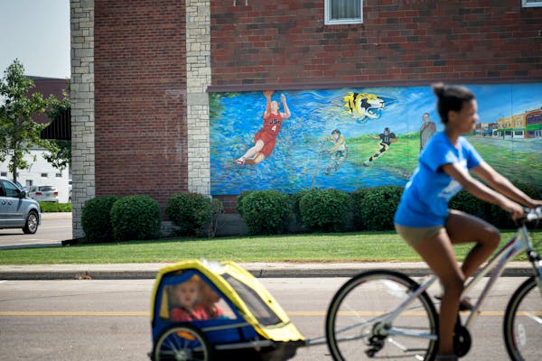Anna Dalbec peddled past the Lindsay Whalen mural with twins Haeden and Chase in tow. She babysits for them and they were on their way to McDonalds do