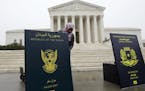 Poster-sized enlargements of passports were put on display outside the Supreme Court by people protesting President Trump's ban on visitors from certa