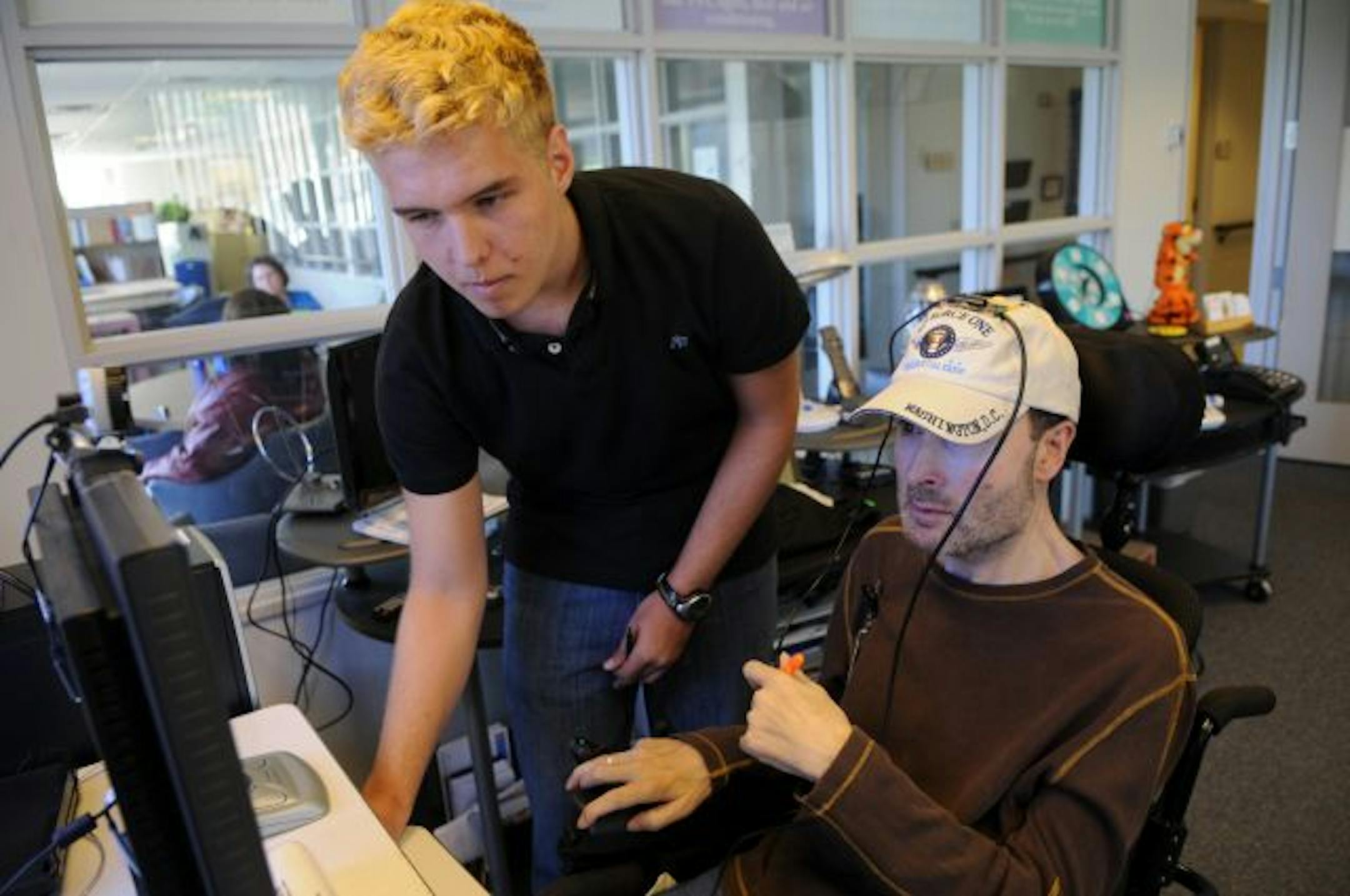 Gavin Ovsak adjusted the controls on a hands-free computer mouse for Scott Moffat of Andover, who was testing it at Courage Center.