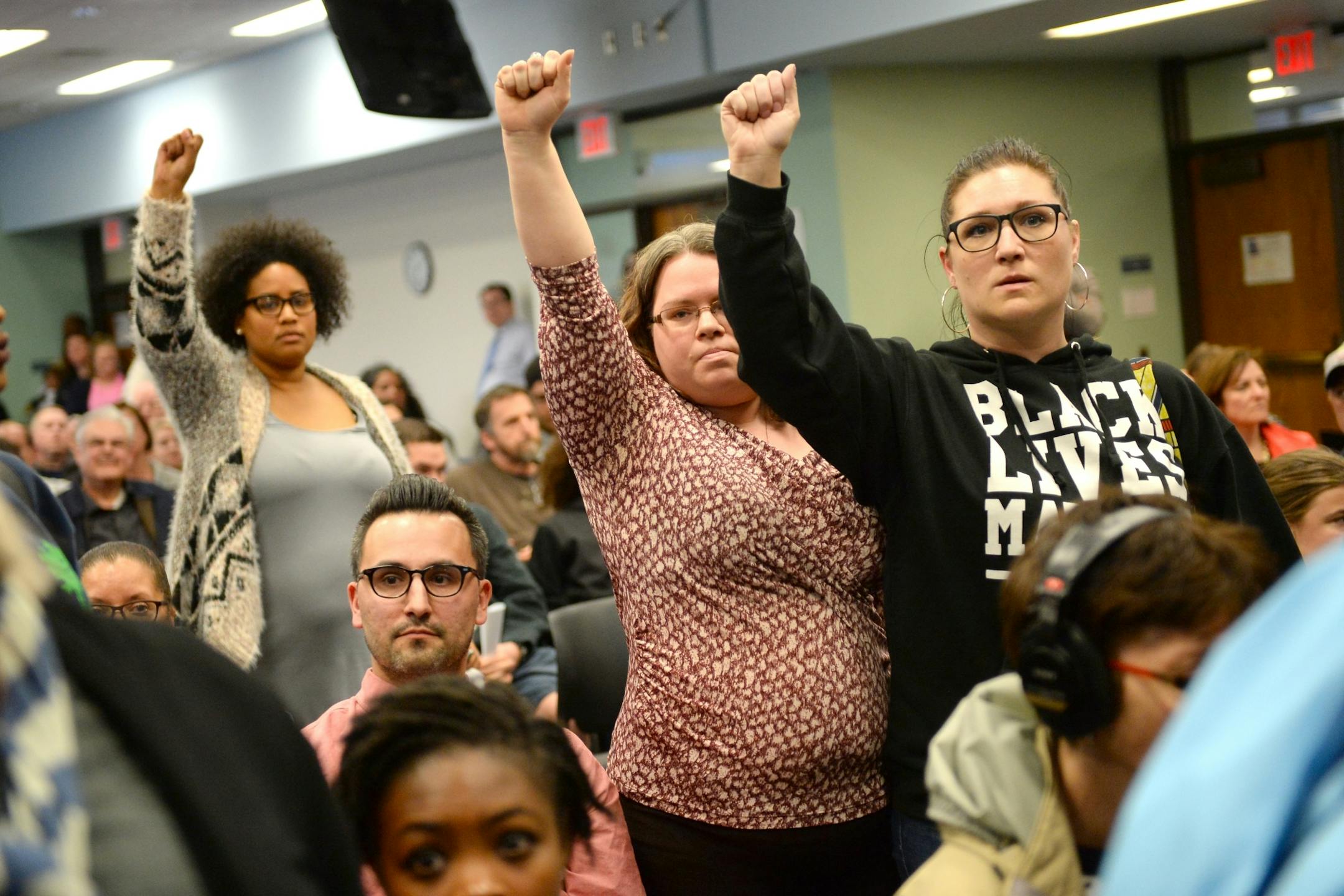 Demonstrators raised their hands in solidarity as Tuesday night's St. Paul School Board meeting's public comment period was interrupted.
