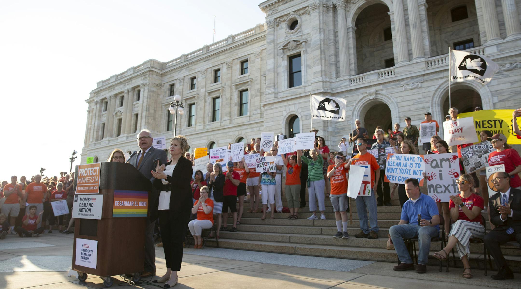 Gov. Tim Walz, flanked by his wife, Gwen, right, and Lt. Gov. Peggy Flanagan, speaks Wednesday, Aug. 7, 2019, during a rally against gun violence at the Minnesota State Capitol in St. Paul. The rally, called "Honor Them With Action: A Rally Against Gun Violence and Hate," was held in the wake of mass shootings in Texas and Ohio. (Christine T. Nguyen/Minnesota Public Radio via AP)