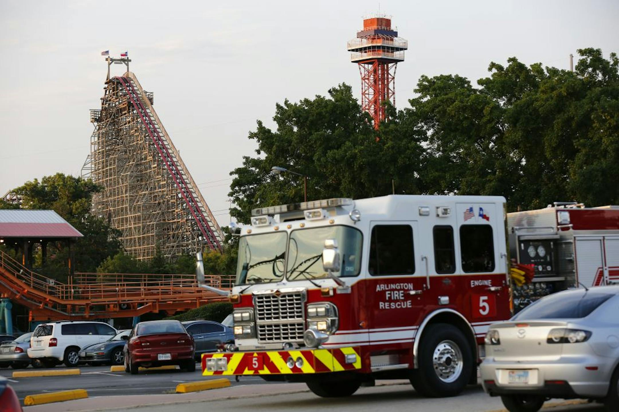 Emergency personnel are on the scene at Six Flags Over Texas in Arlington, Texas, after a woman died on the Texas Giant roller coaster, background left, on Friday, July 19, 2013. (AP Photo/The Dallas Morning News, Tom Fox)