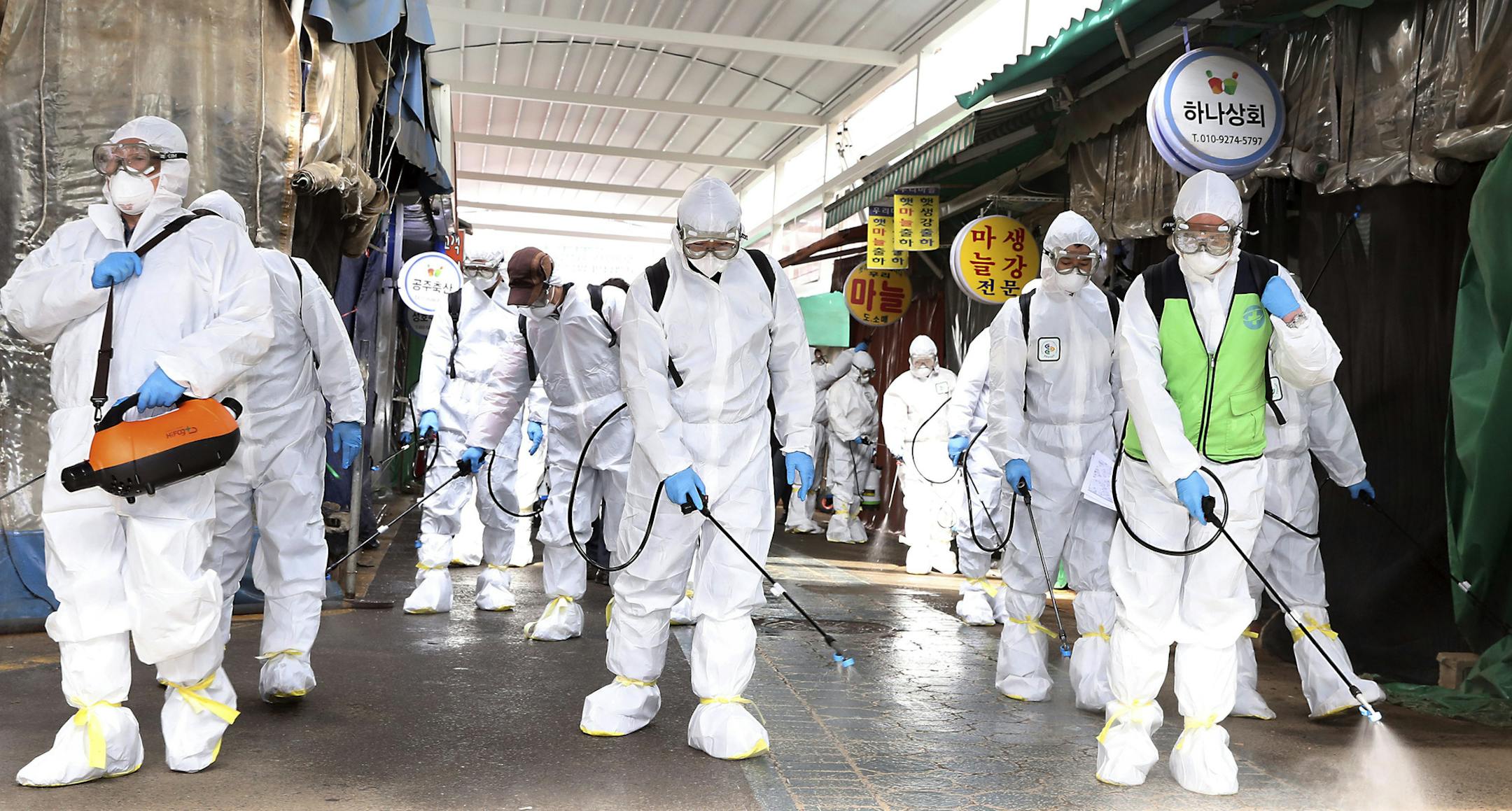Workers wearing protective suits spray disinfectant as a precaution against the coronavirus at a market in Bupyeong, South Korea, Monday, Feb. 24, 2020. South Korea reported another large jump in new virus cases Monday a day after the the president called for "unprecedented, powerful" steps to combat the outbreak that is increasingly confounding attempts to stop the spread. (Lee Jong-chul/Newsis via AP)