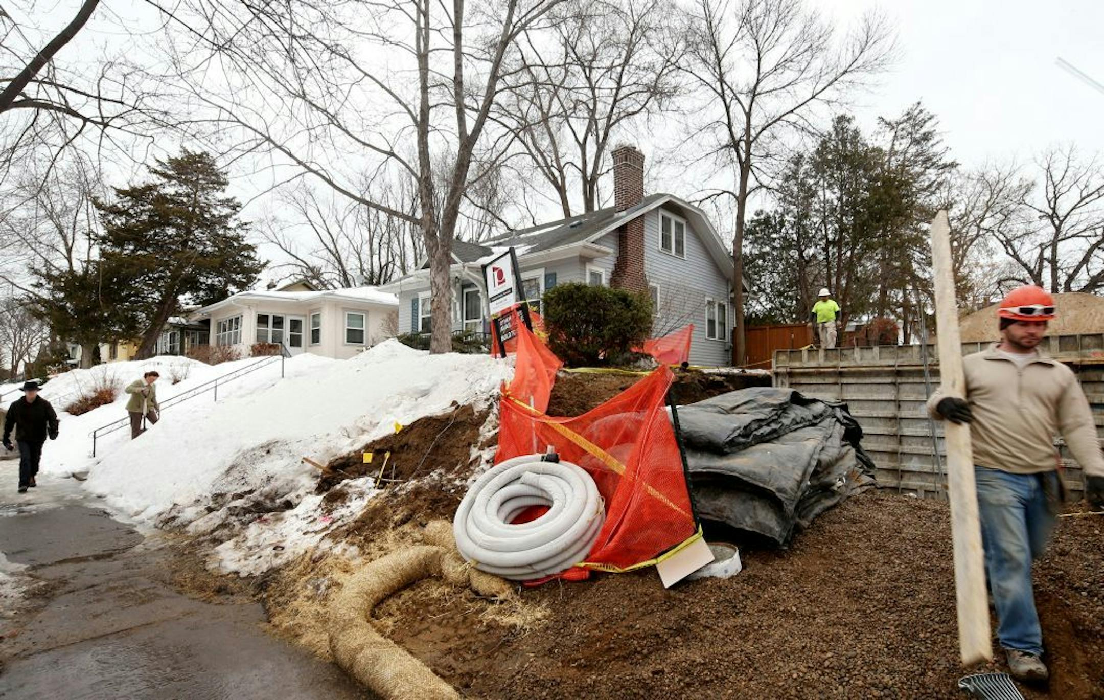 Sharon Potter (left center) of Minneapolis shovels her walkway as construction has started on a teardown next to her home on the 5100 block of York.