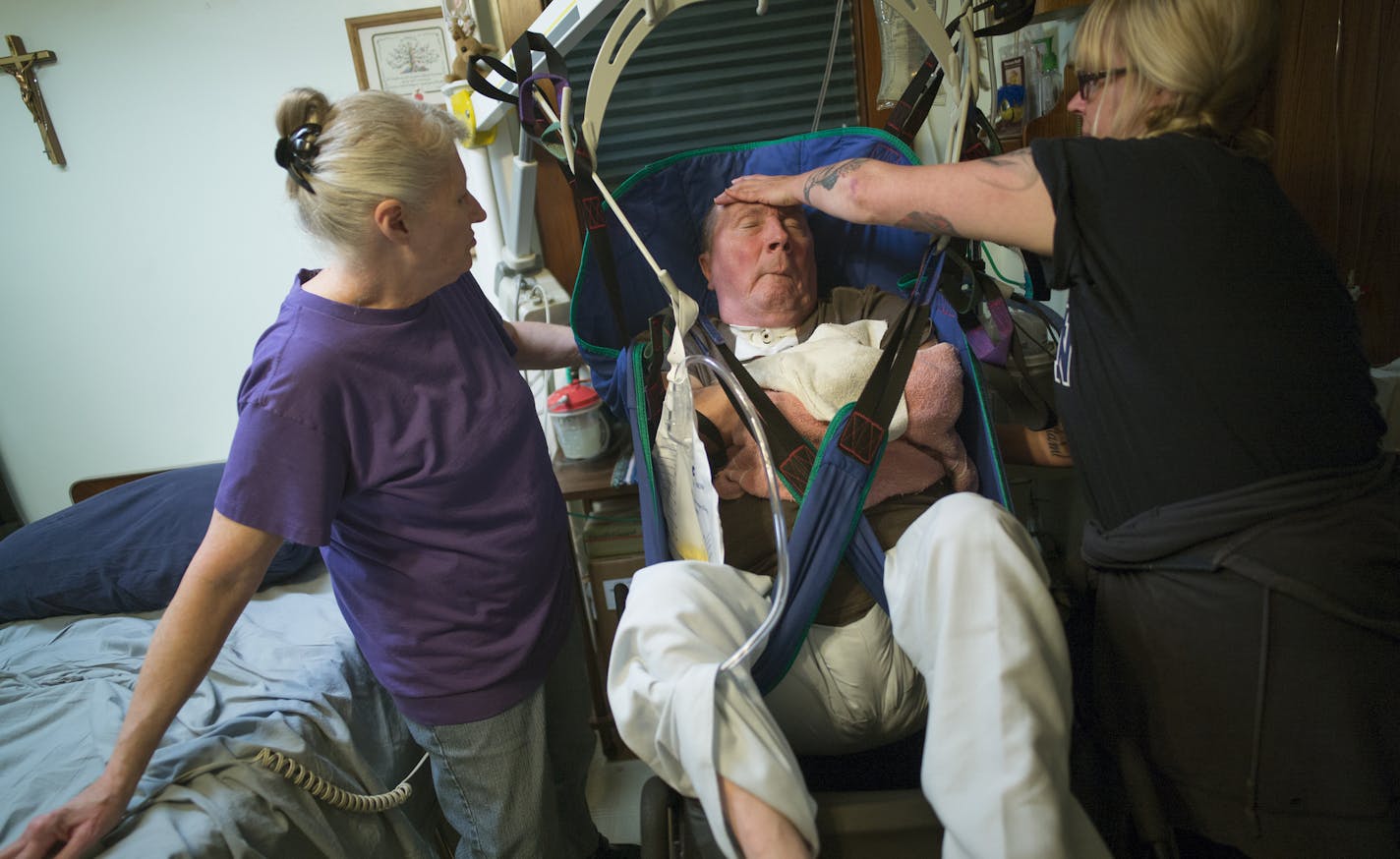 At the home of Linda Jarvis who living room has been turned into a hospital room for husband Gary Jarvis, who suffered a massive stroke and needs 24-hour care, PCA Teri Sernett , right, worked with Linda to put a clean diaper on Gary before moving to his wheelchair using a lift. ] Richard Tsong-Taatarii/rtsong-taatarii@startribune.com