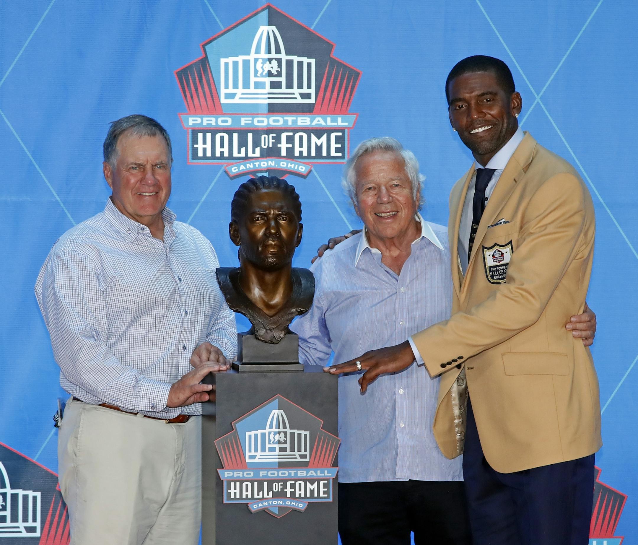 Former NFL player Randy Moss, right, poses with New England Patriots owner Robert Kraft, center, and coach Bill Belichick and a bust of himself during an induction ceremony at the Pro Football Hall of Fame, Saturday, Aug. 4, 2018 in Canton, Ohio.