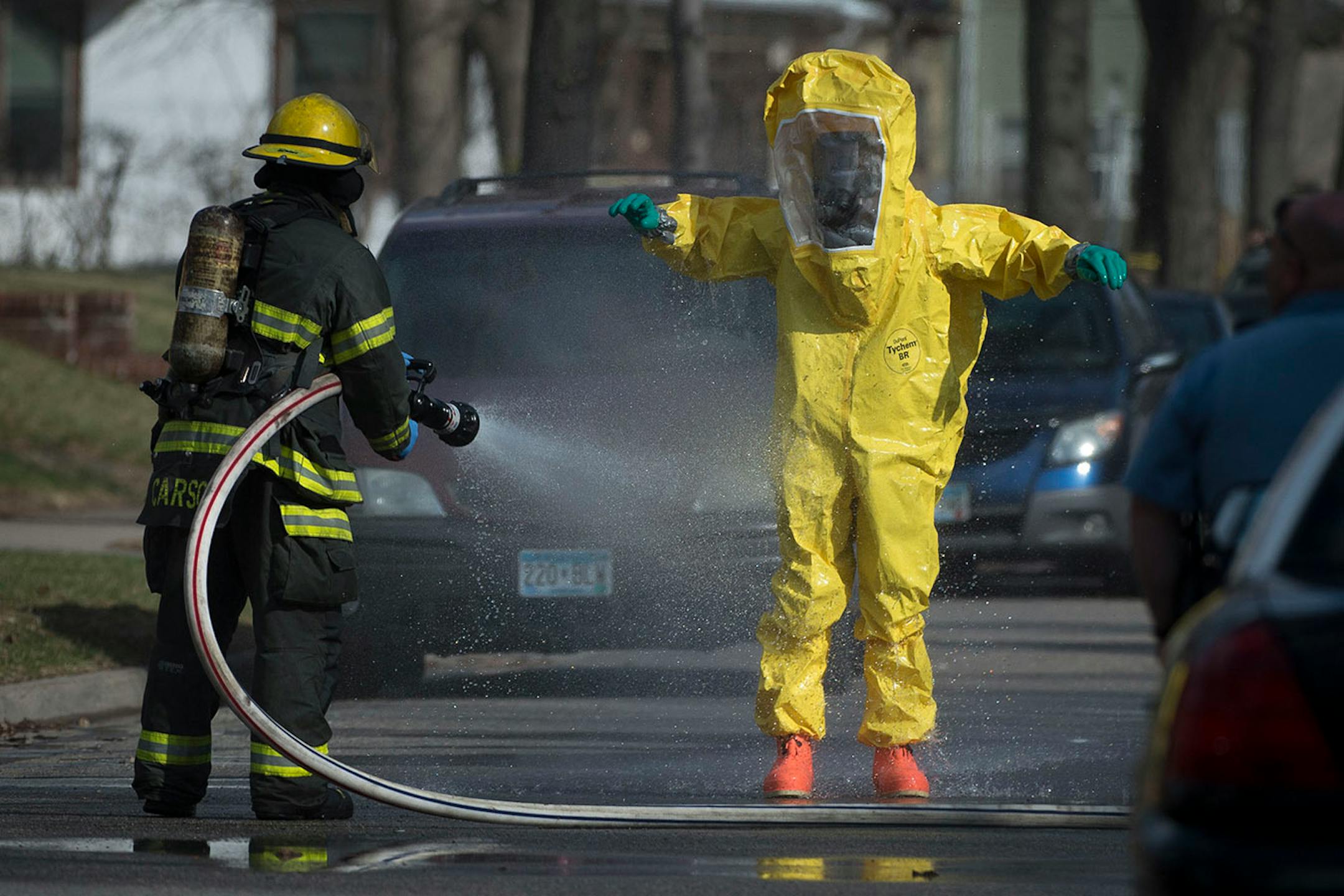 A hazardous material worker is hosed down by a member of the Minneapolis Fire Department after leaving a residence in the Marcy Holmes neighborhood of Minneapolis on the 500 block of 6th Street Southeast on Friday, April 10, 2015.