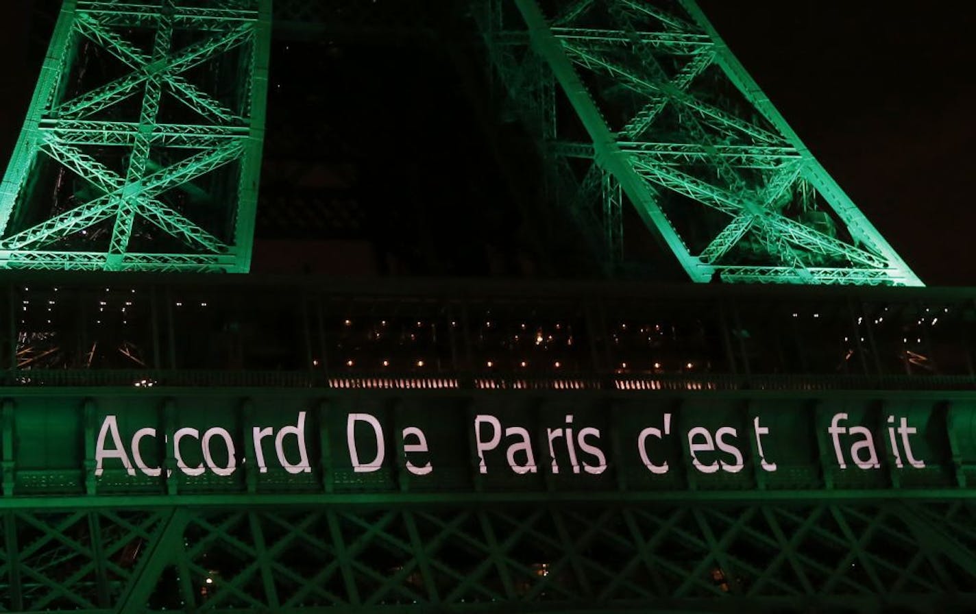 The Eiffel Tower lit up in green to mark the success of the Paris Agreement, Friday Nov.4, 2016 in Paris. The Paris Agreement on climate change enters into force Friday faster than anyone had anticipated, after a year with remarkable success in international efforts to slash man-made emissions of carbon dioxide and other global warming gases. Inscription reads, "Paris Agreement it's done".