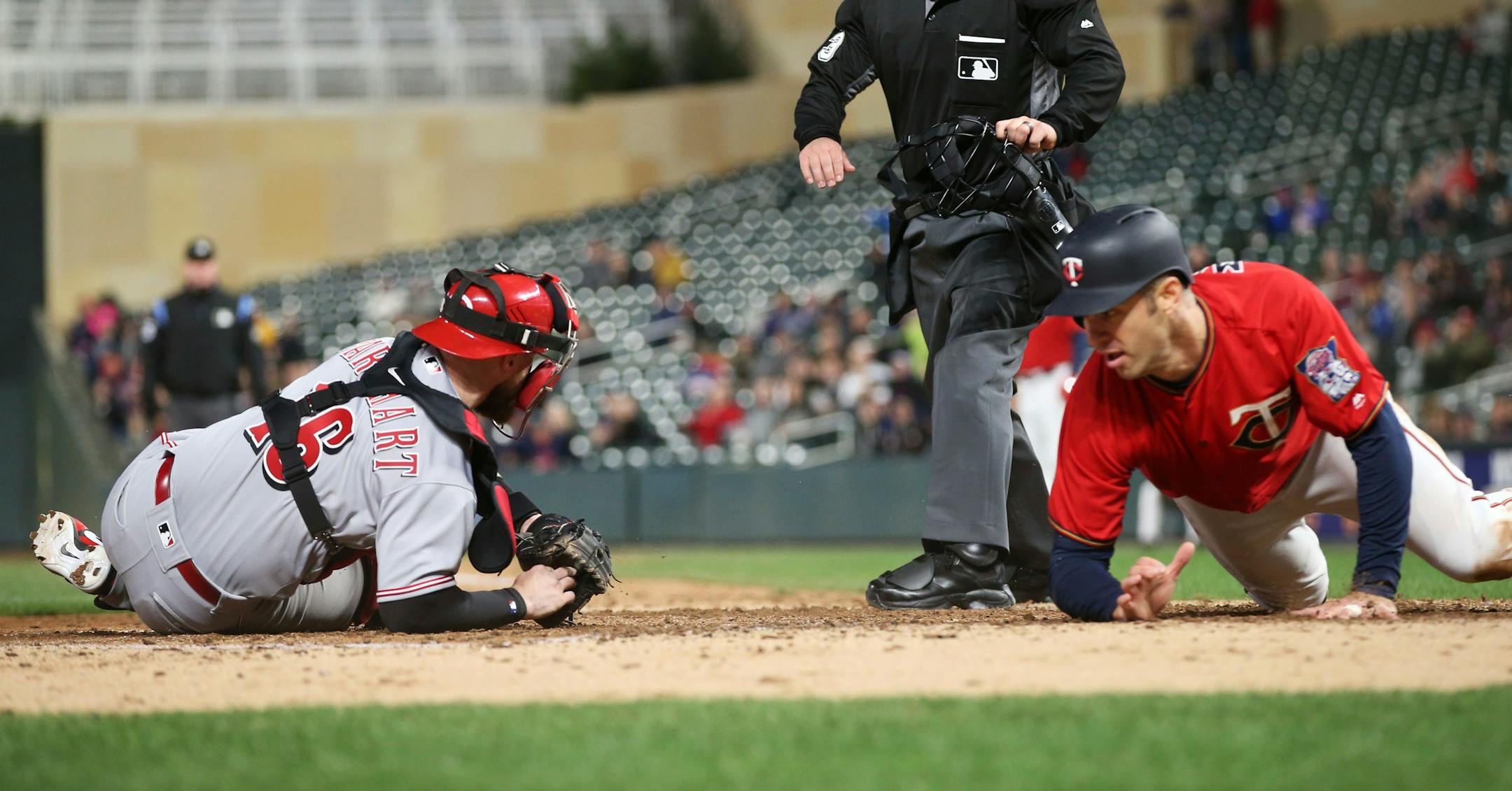 Minnesota Twins' Joe Mauer, right, beats the tag by Cincinnati Reds catcher Tucker Barnhart to score on a double by Max Kepler in the fourth inning of a baseball game Friday, April 27, 2018, in Minneapolis. (AP Photo/Jim Mone)