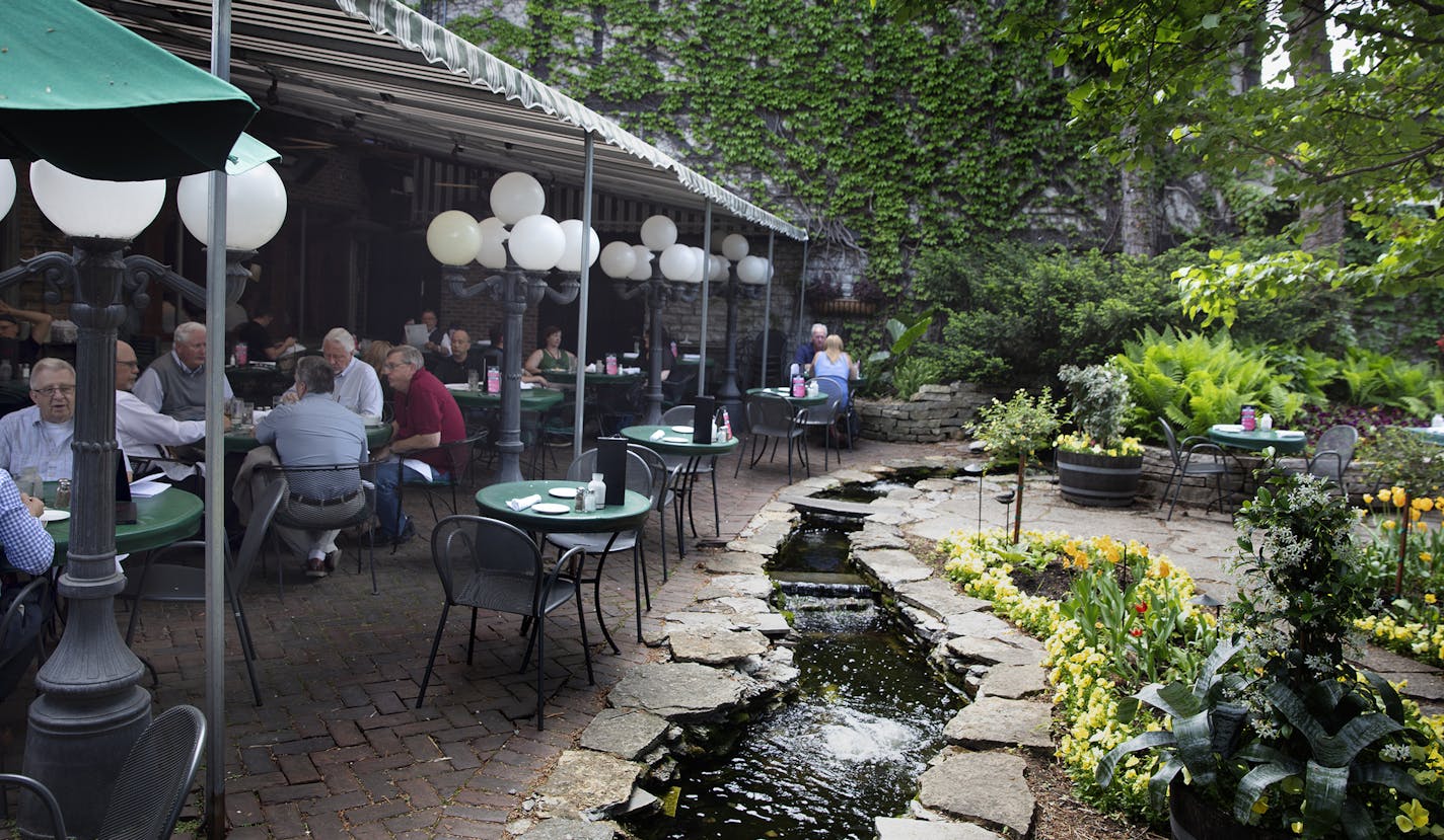 Jax Cafe in northeast Minneapolis. A patio garden, with a stream, a water wheel, flowers, a tented seating area. [ Sidewalks Cafe's Photos by Rick Nelson