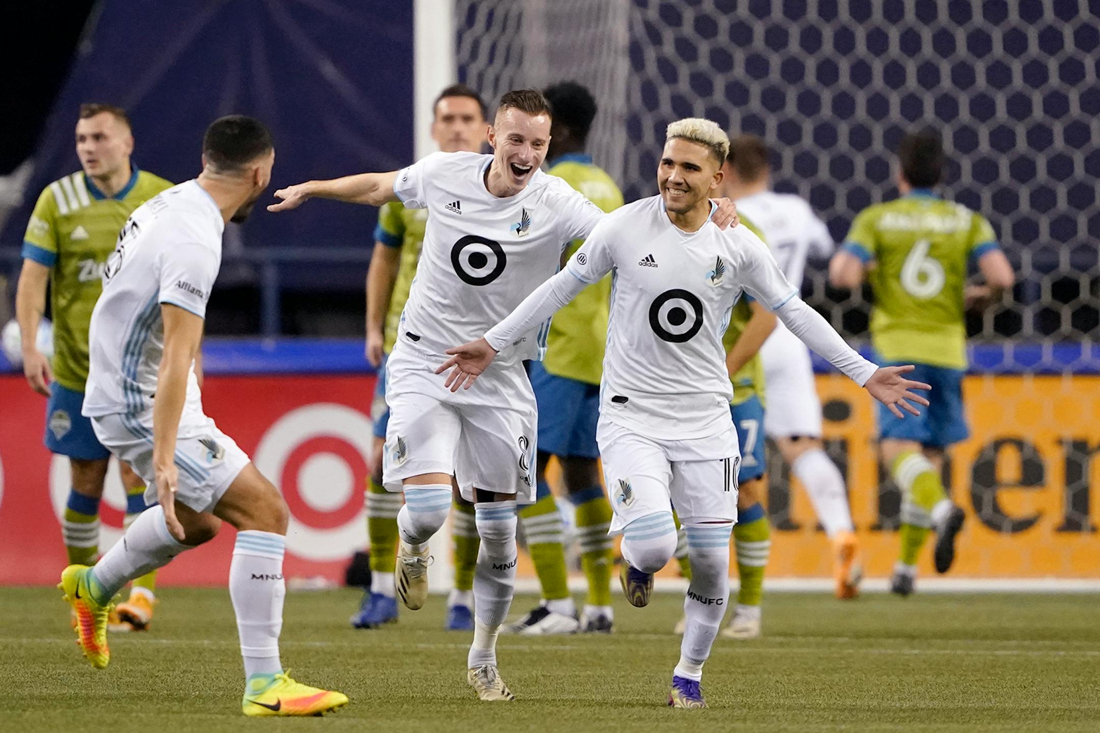 Minnesota United' Emanuel Reynoso, right, celebrates his goal against the Seattle Sounders with teammates Michael Boxall, left, and Jan Gregus during the first half of an MLS playoff Western Conference final soccer match, Monday, Dec. 7, 2020, in Seattle. (AP Photo/Ted S. Warren)