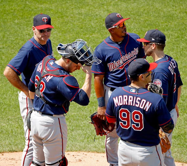 Minnesota Twins manager Paul Molitor, left, meets with his players on the mound while making a pitching change during the seventh inning of a baseball