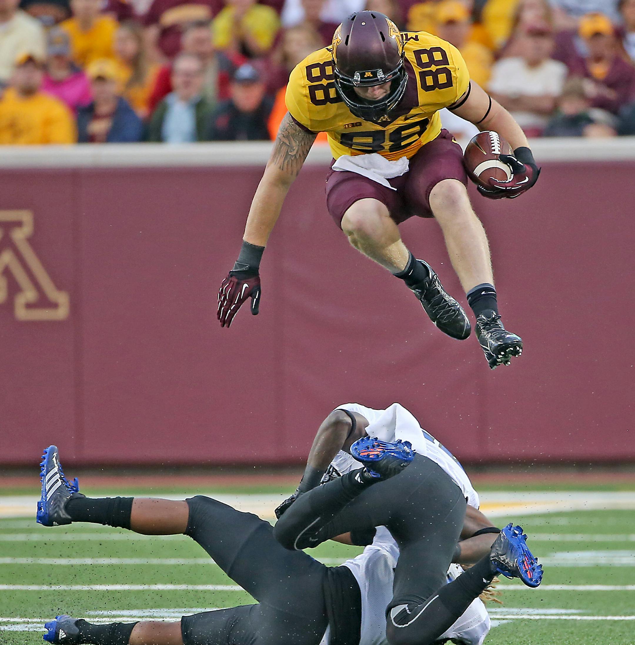 Minnesota tight end Maxx Williams jumped over two Eastern Illinois defenders for a 25 yard catch and run in the season opener, against Eastern Illinois at TCF Bank Stadium, Thursday, August 28, 2014 in Minneapolis, MN. ] (ELIZABETH FLORES/STAR TRIBUNE) ELIZABETH FLORES • eflores@startribune.com ORG XMIT: MIN1408282004569729